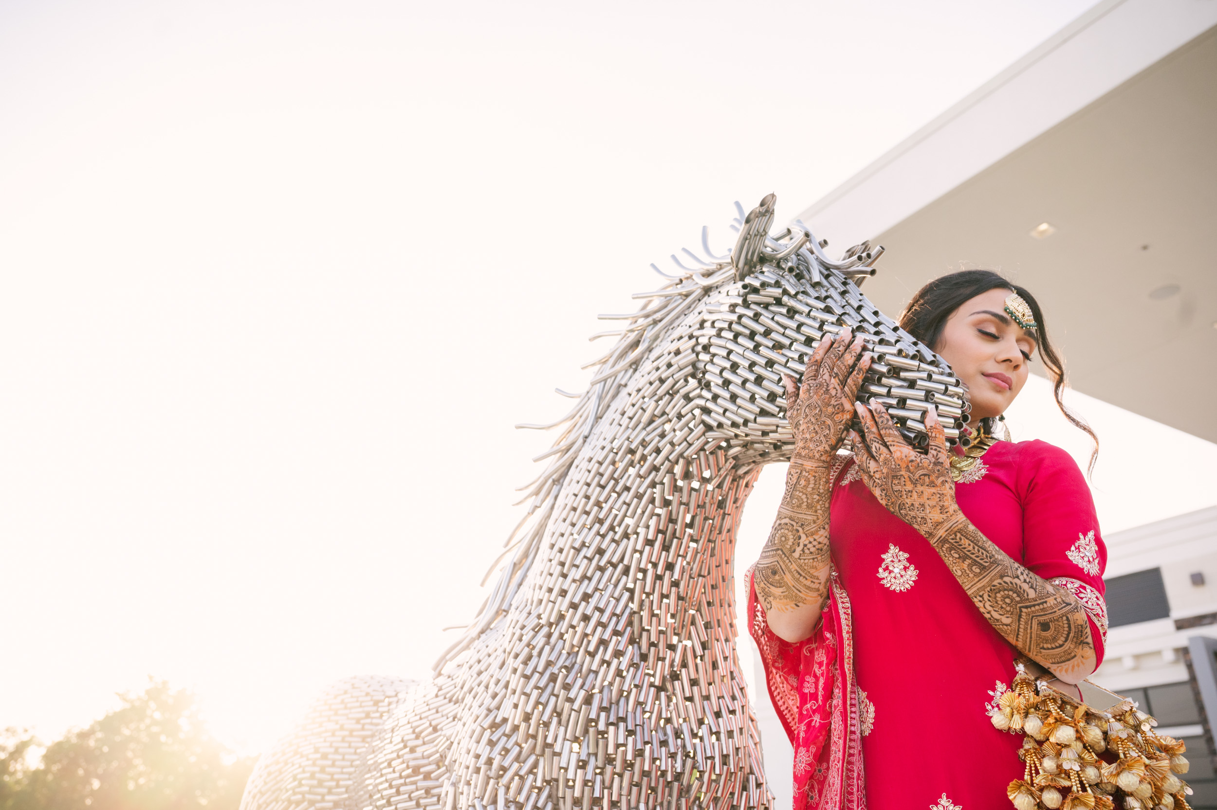 Solo bridal portrait of Anita beside metallic horse sculpture at Alexis Event Venue