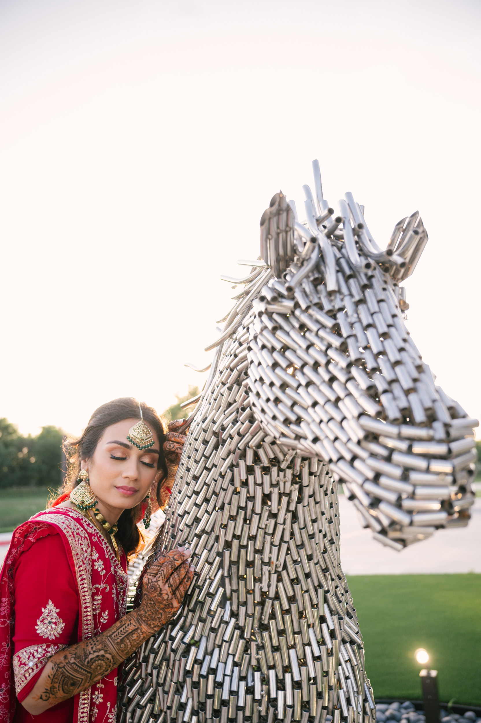 Solo bridal portrait of Anita beside metallic horse sculpture at Alexis Event Venue